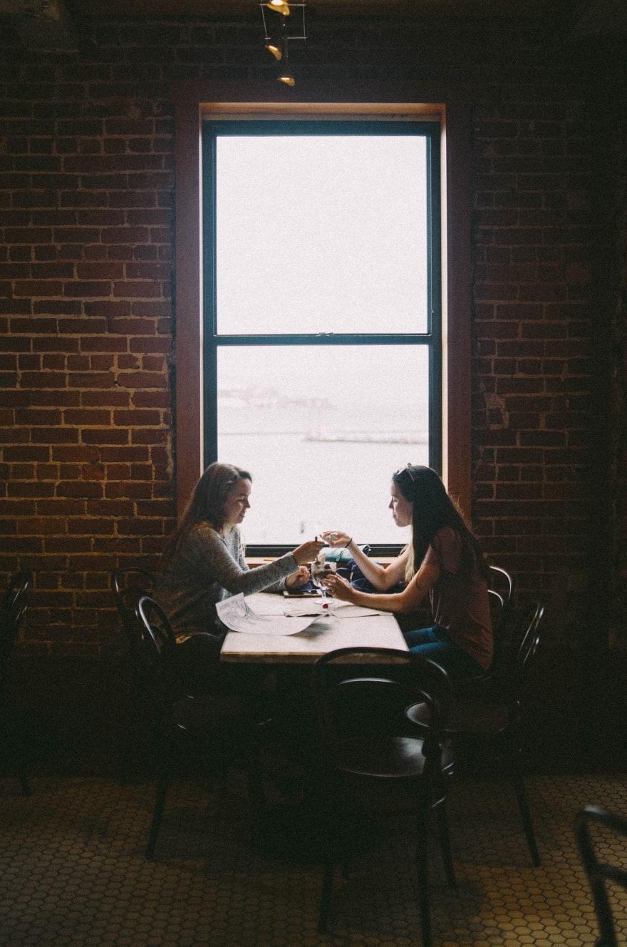 Two girls sitting together and eating icecream in restaurant